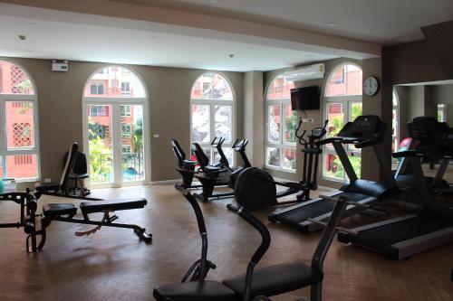 a gym with several treadmills and ellipticals in a room with windows at Seven Seas Jomtien Dream in Jomtien Beach
