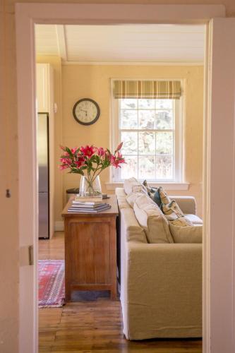 a living room with a couch and a table with flowers at Coldstream Estate - The Whare in Coldstream