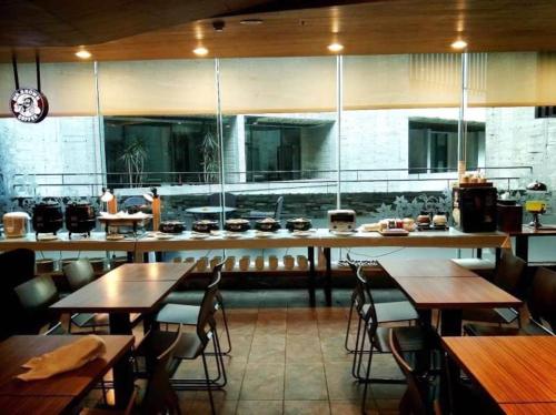 Un restaurante con mesas y sillas y una cocina. en OHYA Chain Boutique Motel-Linkou, en Linkou