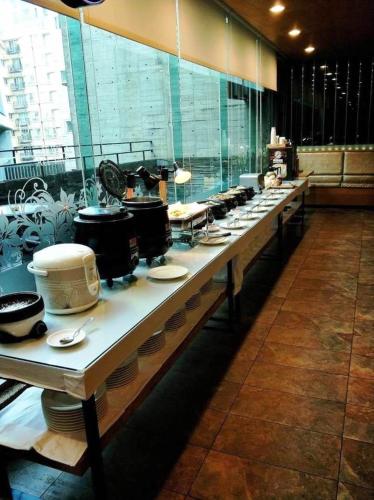 una línea de buffet con platos, ollas y sartenes en OHYA Chain Boutique Motel-Linkou, en Linkou
