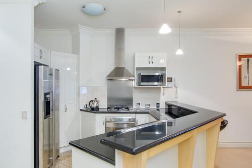 a white kitchen with a black counter top at MacArthur Chambers in Brisbane