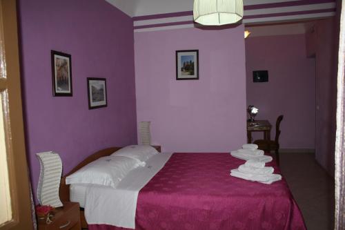 a purple bedroom with a bed with towels on it at Casa Cinema Paradiso in Cefalù