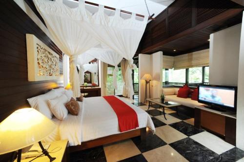 een slaapkamer met een bed en een tv en een bank bij Finna Golf & Country Club in Prigen