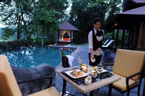 a woman standing next to a table with a plate of food at Finna Golf & Country Club in Prigen