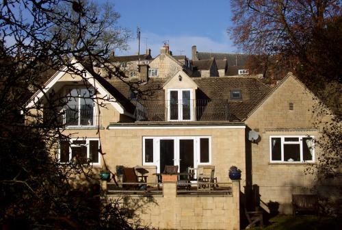 a brick house with chairs on a porch at Tibbiwell Lodge in Painswick