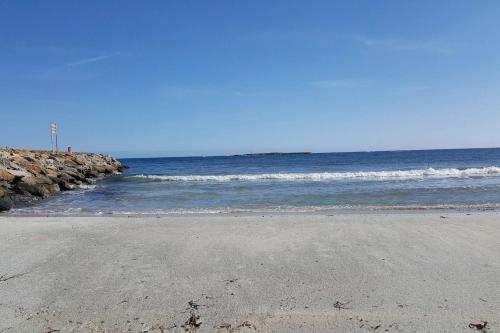 a beach with the ocean and a rocky pier at Lulamax Sardegna in Budoni