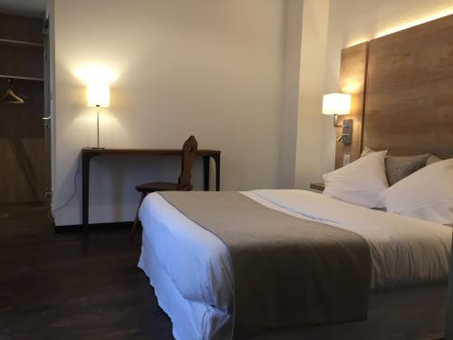 a hotel room with a bed and a chair and lights at Auberge du Rempart in Eguisheim