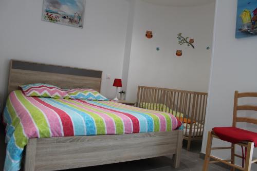 a bedroom with a bed with a colorful striped comforter at Gite à la ferme entre Terre et Mer in Hérenguerville