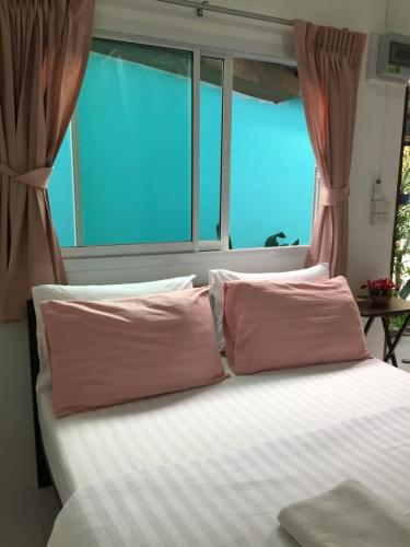 a bed with two pink pillows in front of a window at D Heart Homestay in Bangkok