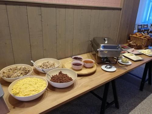 a wooden table with bowls of food on it at Penzion Bílá voda in Harrachov