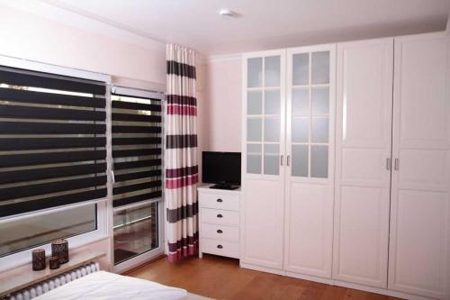 1 dormitorio con armarios blancos, TV y cama en Sonnenschein, en Wenningstedt