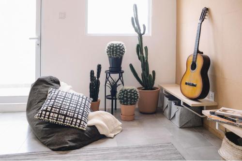 a living room with cacti and a couch with a guitar at Konko Hostel Jakarta in Jakarta