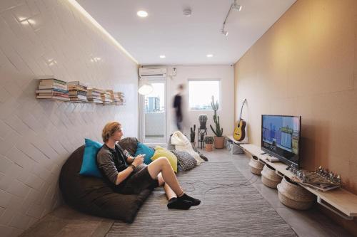 a woman sitting on a couch in a living room at Konko Hostel Jakarta in Jakarta