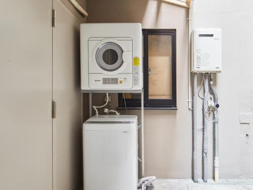 a laundry room with a washing machine and a microwave at Ya Do! KYOTO OKAZAKI in Kyoto