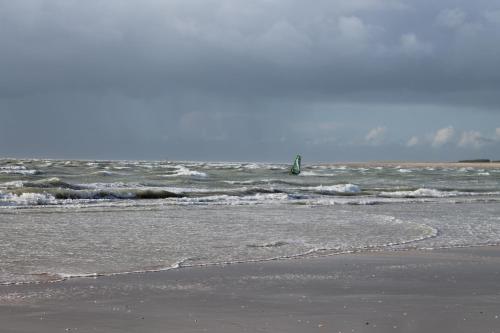 a beach with waves and a person in the ocean at Gite à la ferme entre Terre et Mer in Hérenguerville