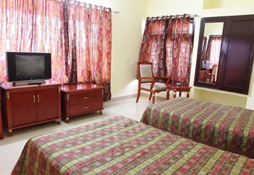 a hotel room with two beds and a flat screen tv at RNS Guest House in Māvalli