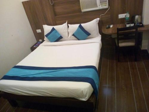 a bed with blue and white pillows in a room at Eclat Suites MINT Gomti Nagar in Lucknow