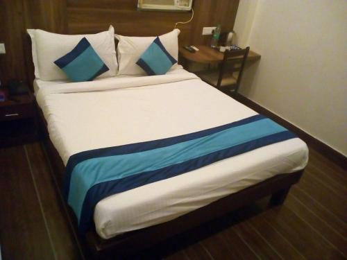 a bed with blue and white pillows in a room at Eclat Suites MINT Gomti Nagar in Lucknow