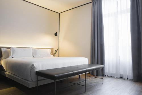 a bedroom with a bed and a bench next to a window at ICON Embassy in Madrid