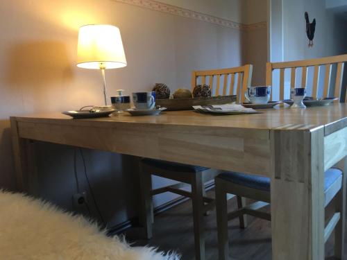 a wooden table with two chairs and a lamp at Ferienhaus Janik in Friedrichskoog