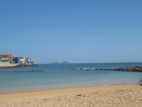a beach with the ocean and buildings in the background at Residencialdes in São Tomé