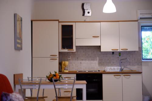 a kitchen with white cabinets and a table with chairs at Patras Palm Tree in Patra