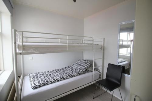 a bedroom with two bunk beds and a chair at Steinaskjól Apartments in Akureyri