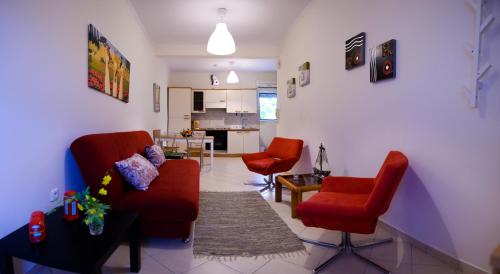 ein Wohnzimmer mit 2 roten Stühlen und eine Küche in der Unterkunft Patras Palm Tree in Patras
