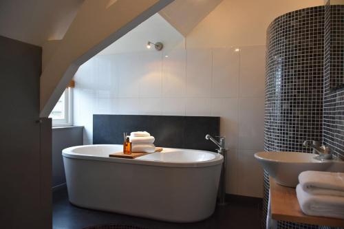 een badkamer met een groot bad en een wastafel bij Zzzuite25 in Oosterhout