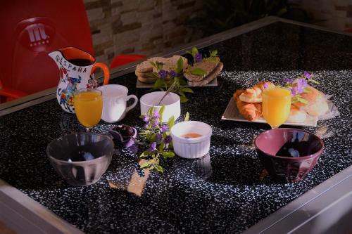une table avec des tasses et des assiettes de nourriture et de jus d'orange dans l'établissement Posada Chloe Santiago, à Santiago de la Ribera