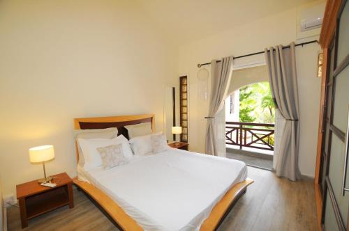 a bedroom with a large bed and a balcony at Kenville 9 in Pereybere