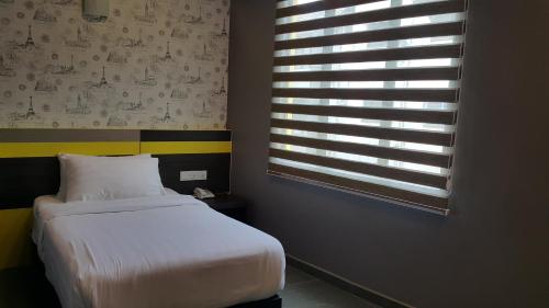 a bedroom with a white bed and a window at Kampar Boutique Hotel in Kampar