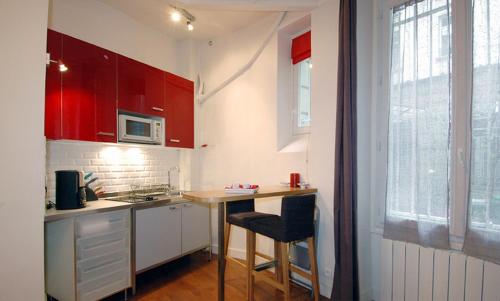 a small kitchen with red cabinets and a counter at Studio Saint Sulpice in Paris