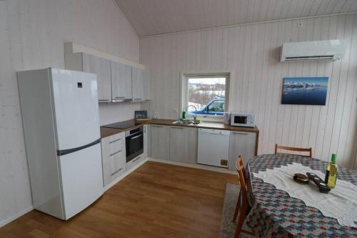 a kitchen with a table and a white refrigerator at Aurora View Cabin in Lyngseidet
