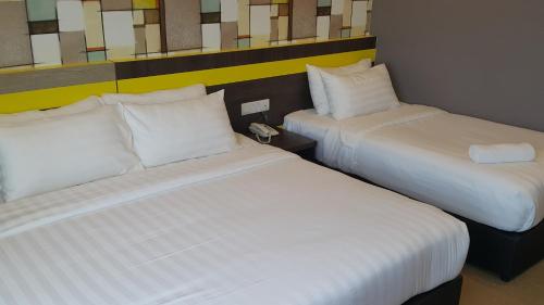 two beds sitting next to each other in a room at Kampar Boutique Hotel in Kampar