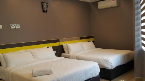two beds in a hotel room with white sheets at Kampar Boutique Hotel in Kampar