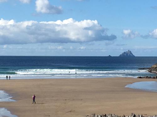 a person walking on a beach near the ocean at Chapel Cross House in Ballinskelligs