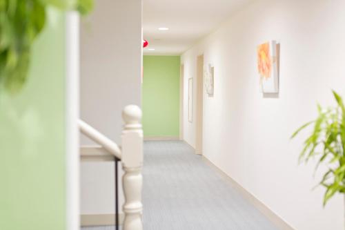 a hallway with white walls and stairs with plants at Shin-Okubo City Hotel in Tokyo