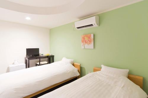 a bedroom with two beds and a air conditioner at Shin-Okubo City Hotel in Tokyo