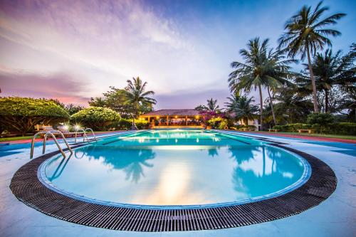 a swimming pool at a resort with palm trees at Hotel Yapahuwa Paradise in Yapahuwa