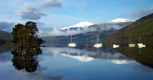 a group of boats in a lake with mountains at Mains of Taymouth Country Estate 5* Gallops Apartments in Kenmore