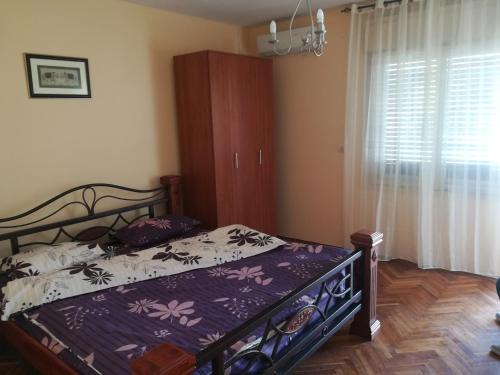 een slaapkamer met een bed met een paars dekbed en een raam bij Sweet Dream Rooms in Podgorica