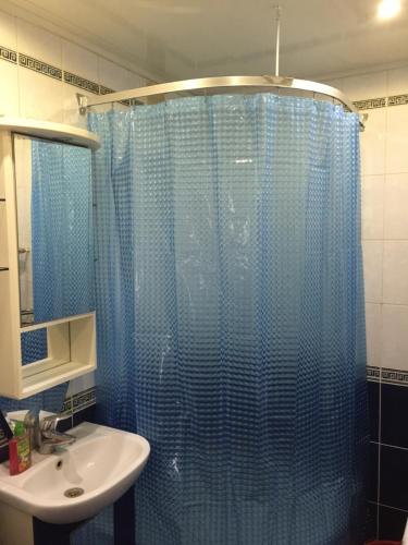 a bathroom with a blue shower curtain and a sink at Apartment On Oktyabrskaya 4 in Ukhta