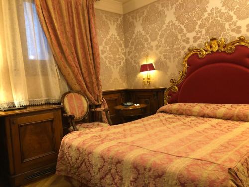 a bedroom with a bed with a red headboard and a window at Bellevue Luxury Rooms - San Marco Luxury in Venice