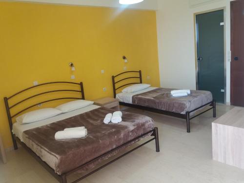 two beds in a room with yellow walls at Nikos & Anna Rooms in Rodakino