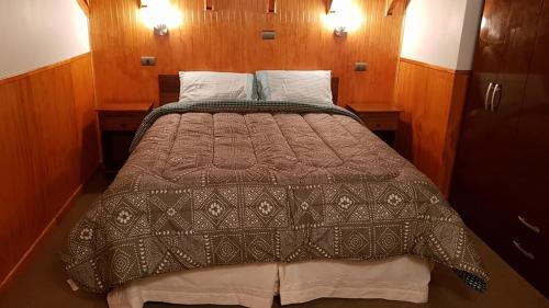a large bed in a room with wooden walls at Cabañas Rayen in Río Bueno