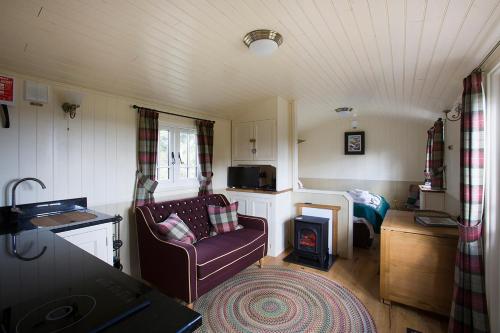 a small living room with a couch and a stove at The Hideaway Huts in Bardon Mill