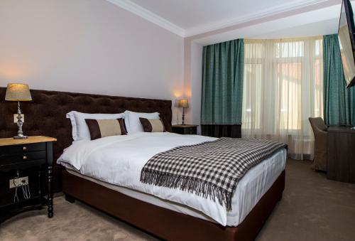 a bedroom with a large bed with green curtains at ZENTRUM Hotel in Chişinău