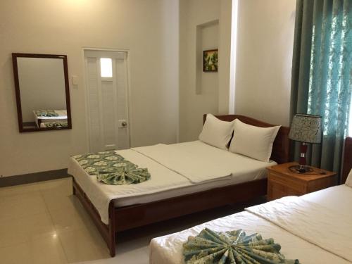 a bedroom with two beds and a mirror at Minh Nhi Hotel in La Gi