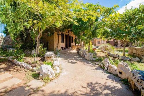 une passerelle dans un jardin avec des arbres et des rochers dans l'établissement Masseria Borgo del Gallo, à Tricase